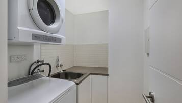 A compact kitchen with a built-in washer and dryer, a sink, and a door with a handle.