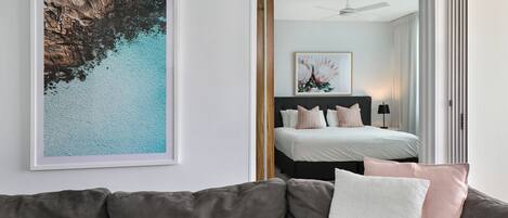 Un dormitorio moderno con cama, mesita de noche y una obra de arte enmarcada en la pared.