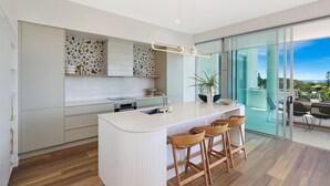 Une cuisine moderne dotée d’un îlot central, de tabourets de bar et offrant une vue sur l’extérieur.
