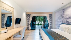 Un hotel moderno con una cama grande, un escritorio con silla, un televisor y vistas a árboles por la ventana.