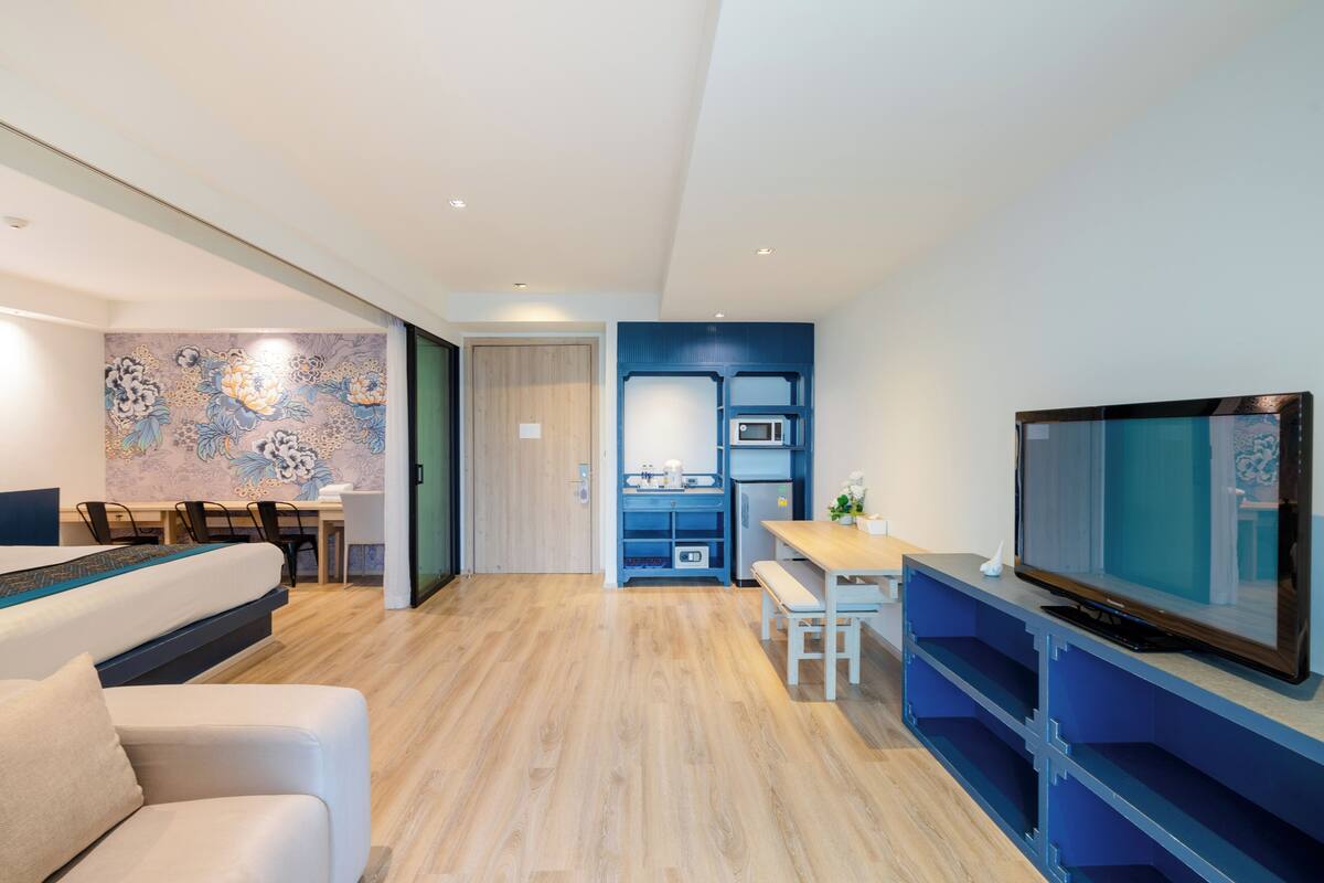 Ett modernt hotellrum med en säng, en TV, ett skrivbord och ett litet pentry.
