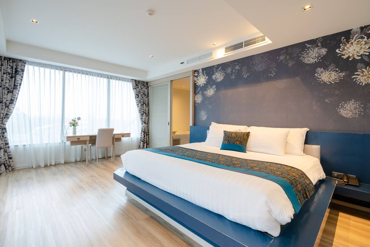 Ett modernt hotellrum med en stor säng, ett skrivbord och en stol.