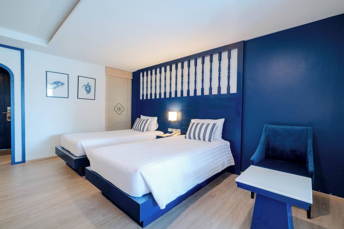 Ett modernt hotellrum med två sängar, ett skrivbord och en stol.