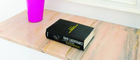 A room with a large mirror, a white sofa, a small table, and a book titled "David Lagercrantz".
