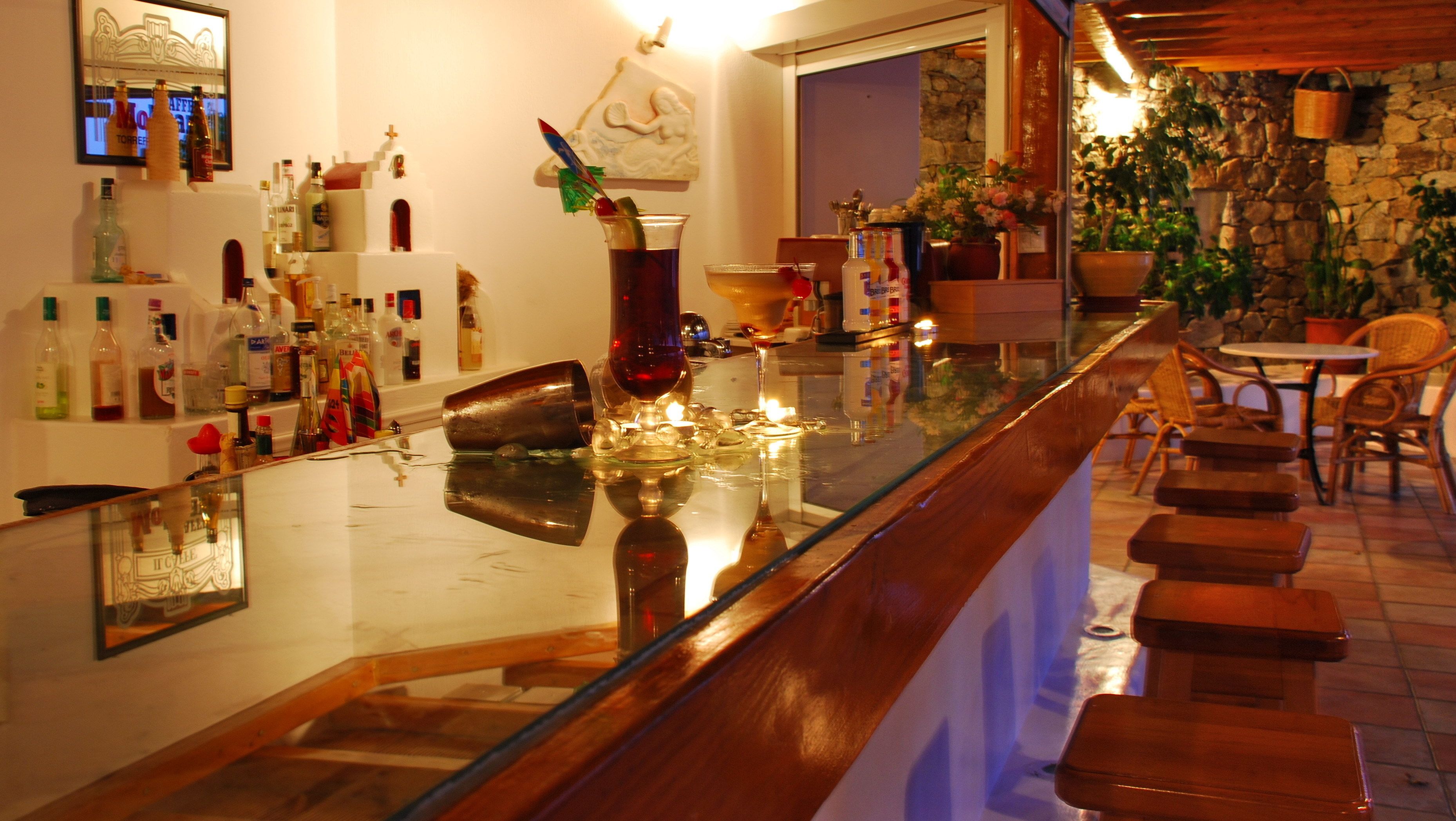A bar area with a glass counter, various bottles, and a decorative mirror.