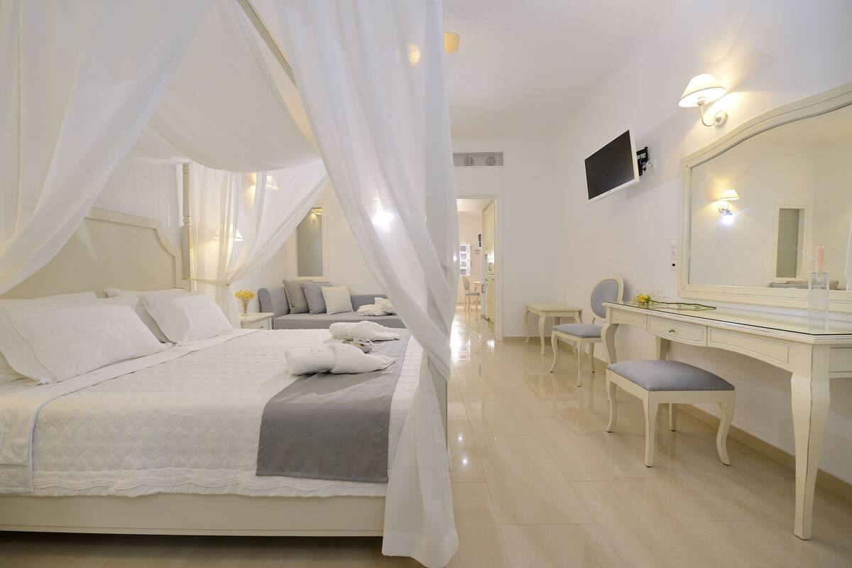 A bedroom with a bed, a desk, a chair, and a large mirror.