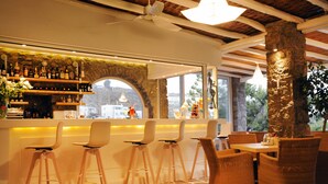 Uma área de bar com banquetas, piso de pedra e vista por uma grande janela.
