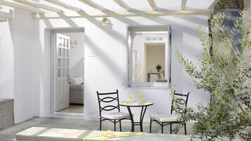 A patio with a table and chairs, a mirror, and a stone wall.