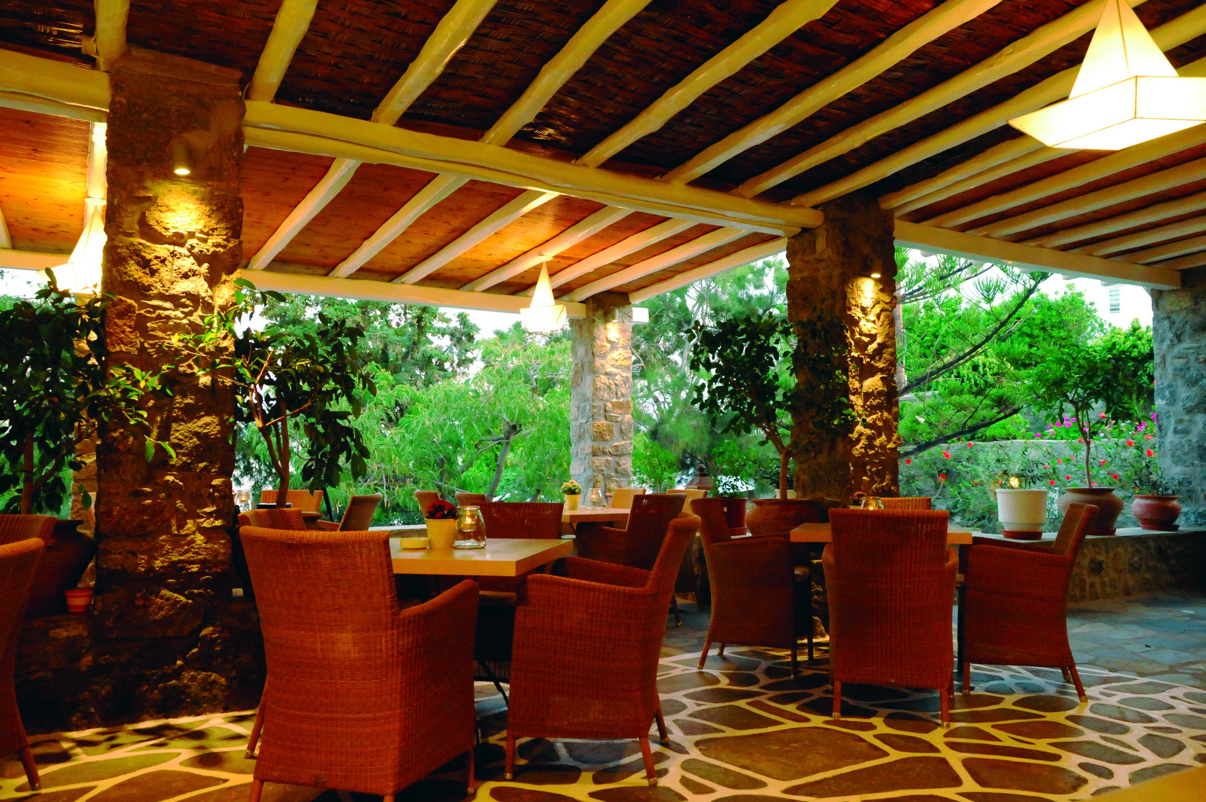 An outdoor dining area with stone pillars, wicker chairs, and tables.