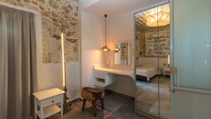 Een moderne slaapkamer met een stenen muur, nachtkastje, spiegel en bed.