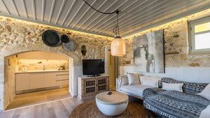 Een moderne woonkamer met een stenen muur, een flatscreen televisie, een bank en een ronde salontafel.