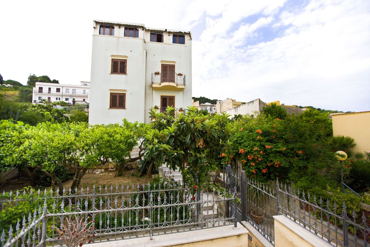 A white building with balconies and a garden in front.