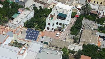 An aerial view of a residential area with buildings, solar panels, and a palm tree.