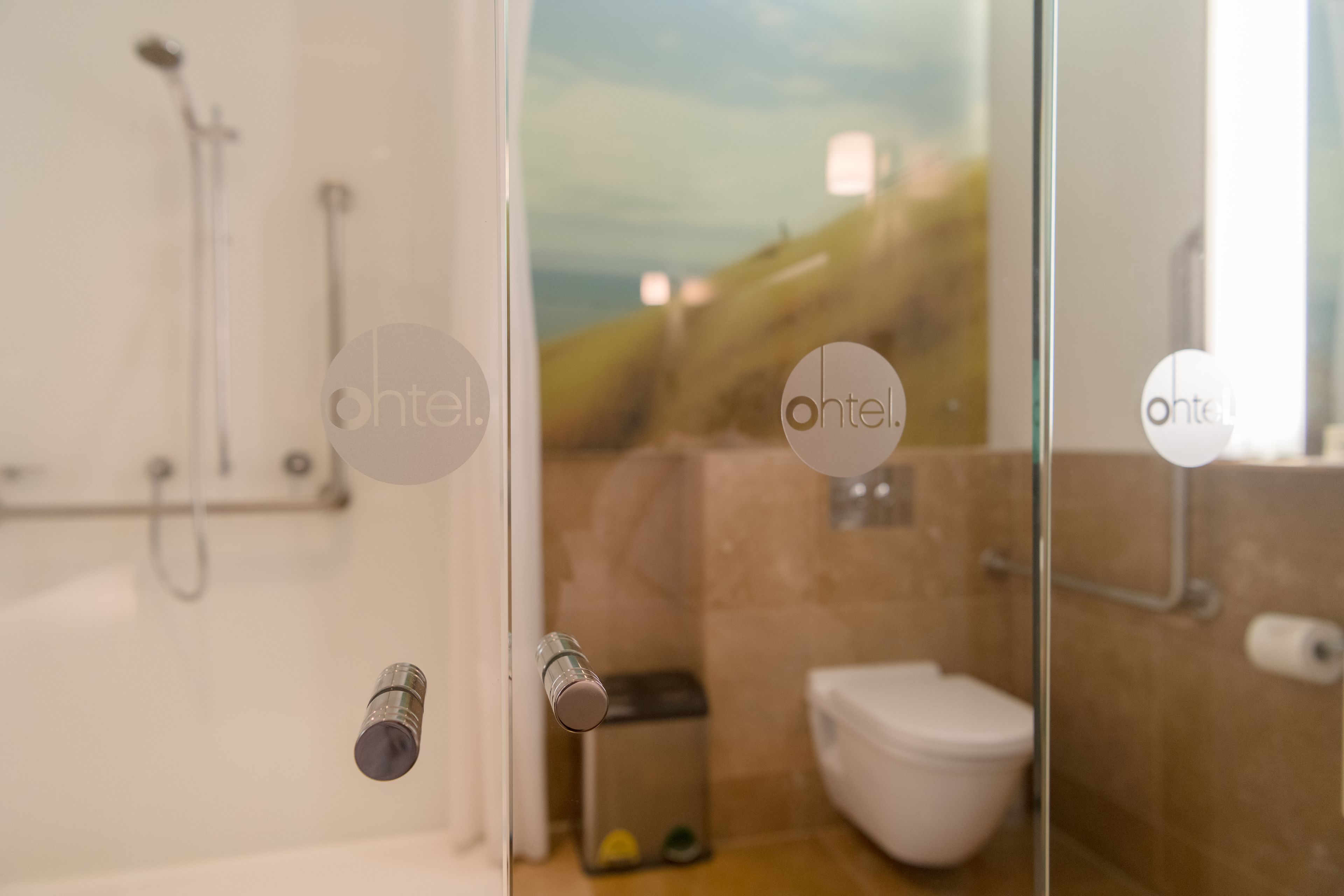 A bathroom with a glass door, a shower, a toilet, and a sink.