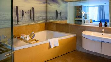 A modern bathroom with a large bathtub, a separate sink, and a glass shower enclosure.