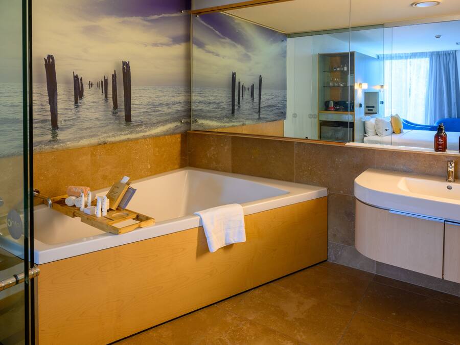 A modern bathroom with a large bathtub, a separate sink, and a glass shower enclosure.