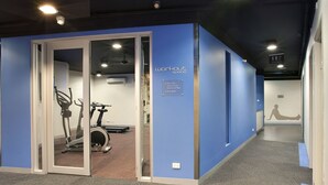 A workout space with exercise equipment, a sign indicating the location, and a wall-mounted sign with a silhouette of a person exercising. - Space Hotel - Hostel (Melbourne)