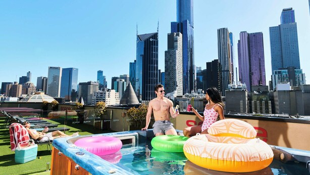 A rooftop pool with inflatable rings and a city skyline in the background. - Space Hotel - Hostel (Melbourne)