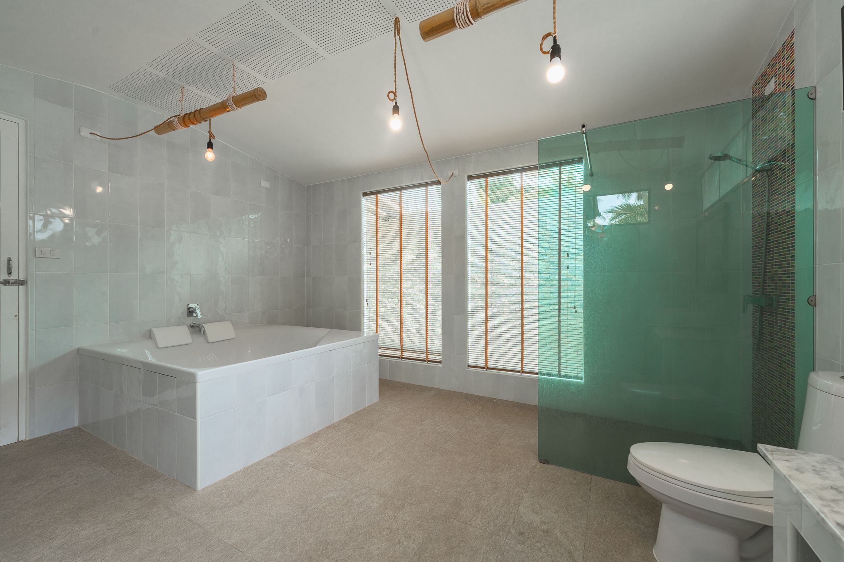 Et moderne badeværelse med badekar på fod, glasafskærmet brusebad og toilet.