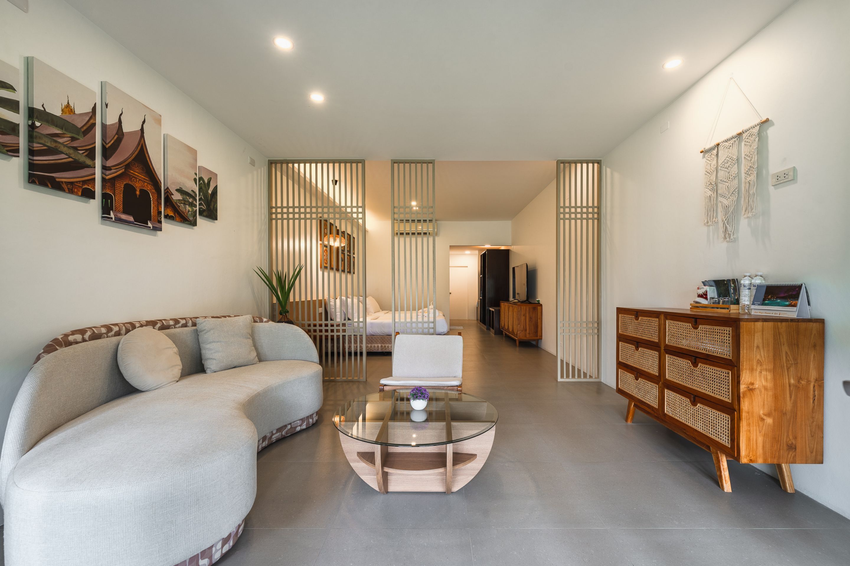 A modern living room with a curved sofa, a glass coffee table, and a wooden cabinet.