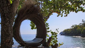 A hammock chair under a large tree by a beach with clear blue water and a rocky shoreline. - Ban Raya Resort and Spa (Ko Racha Yai)