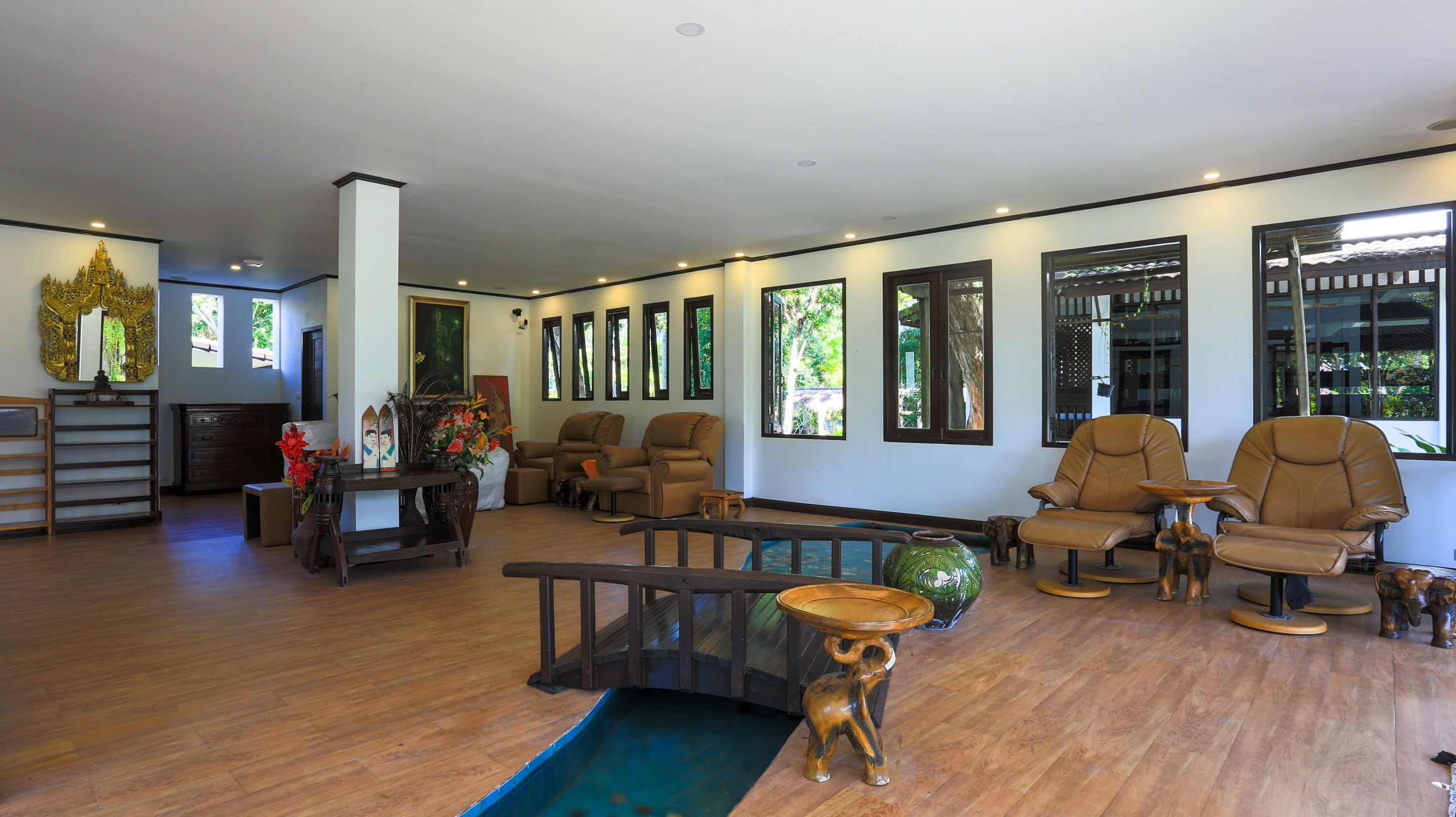 A spacious living room with a wooden floor, multiple seating options including sofas and chairs, a coffee table, and a decorative vase.