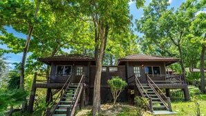Two wooden cabins with external stairs, surrounded by lush greenery and trees. - Ban Raya Resort and Spa (Ko Racha Yai)
