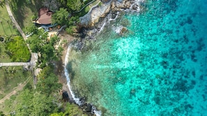 An aerial view of a coastal property with clear turquoise waters, rocky shoreline, and lush greenery. - Ban Raya Resort and Spa (Ko Racha Yai)