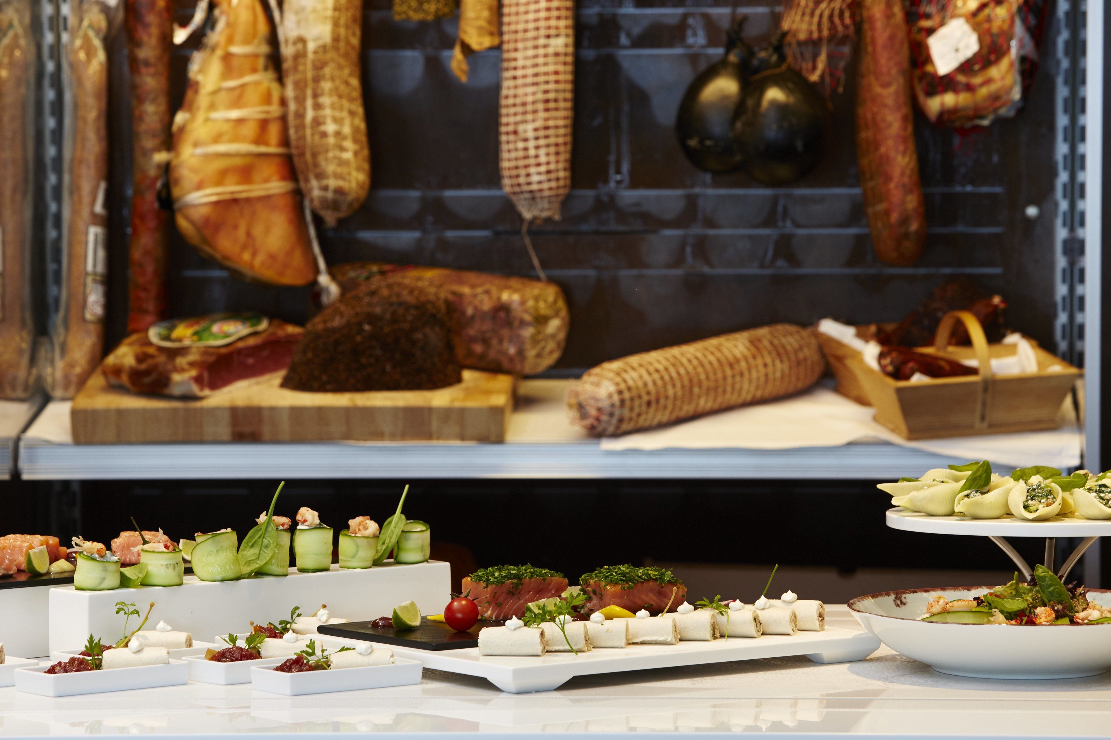 Variedad de alimentos servidos en un restaurante, incluyendo carnes, quesos y aperitivos.