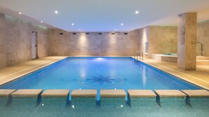 A large indoor swimming pool with clear blue water, tiled walls, and a star design on the floor. - The Esplanade Hotel (Newquay)