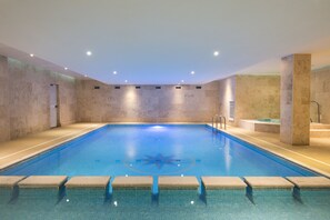 A large indoor swimming pool with clear blue water, tiled walls, and a star design on the floor. - The Esplanade Hotel (Newquay)