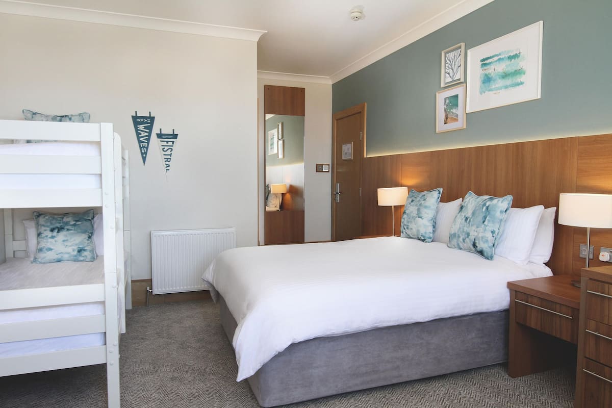 A bedroom with a bunk bed, a large bed, and a nightstand.