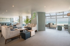 A spacious lounge area with multiple seating options, a large window offering a view of the ocean, and a modern interior design. - The Esplanade Hotel (Newquay)