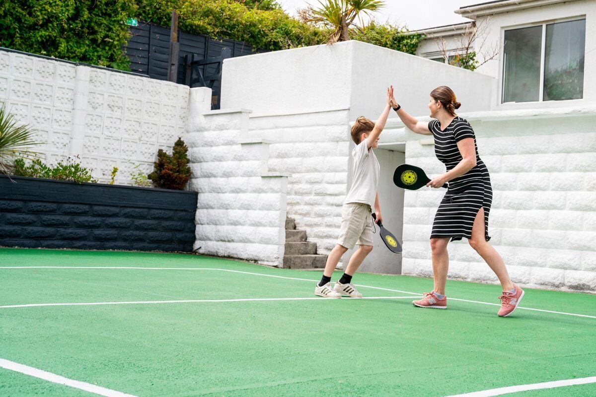 A tennis court with a white wall and a black fence.