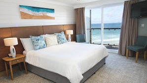 A hotel room with a large bed, two bedside tables with lamps, a chair, a TV, and a large window with a view of the ocean. - The Esplanade Hotel (Newquay)