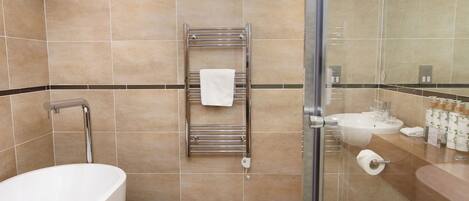 A modern bathroom with a freestanding bathtub, a glass shower enclosure, and a towel rack with a single towel.