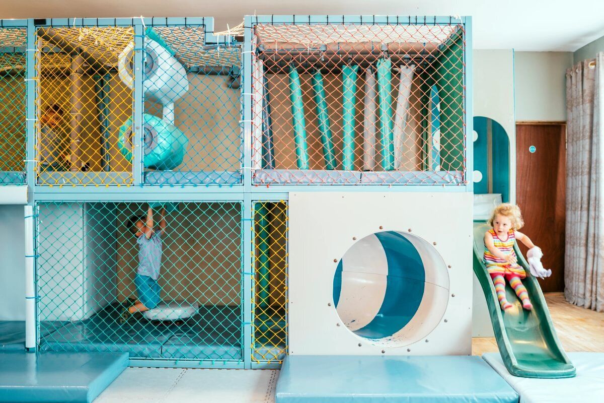 A multi-level play structure with slides and climbing areas, enclosed by a safety net.