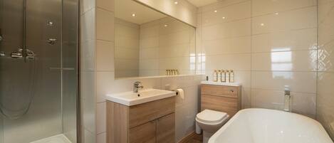 A modern bathroom with a glass-enclosed shower, a freestanding bathtub, and a vanity with a mirror.