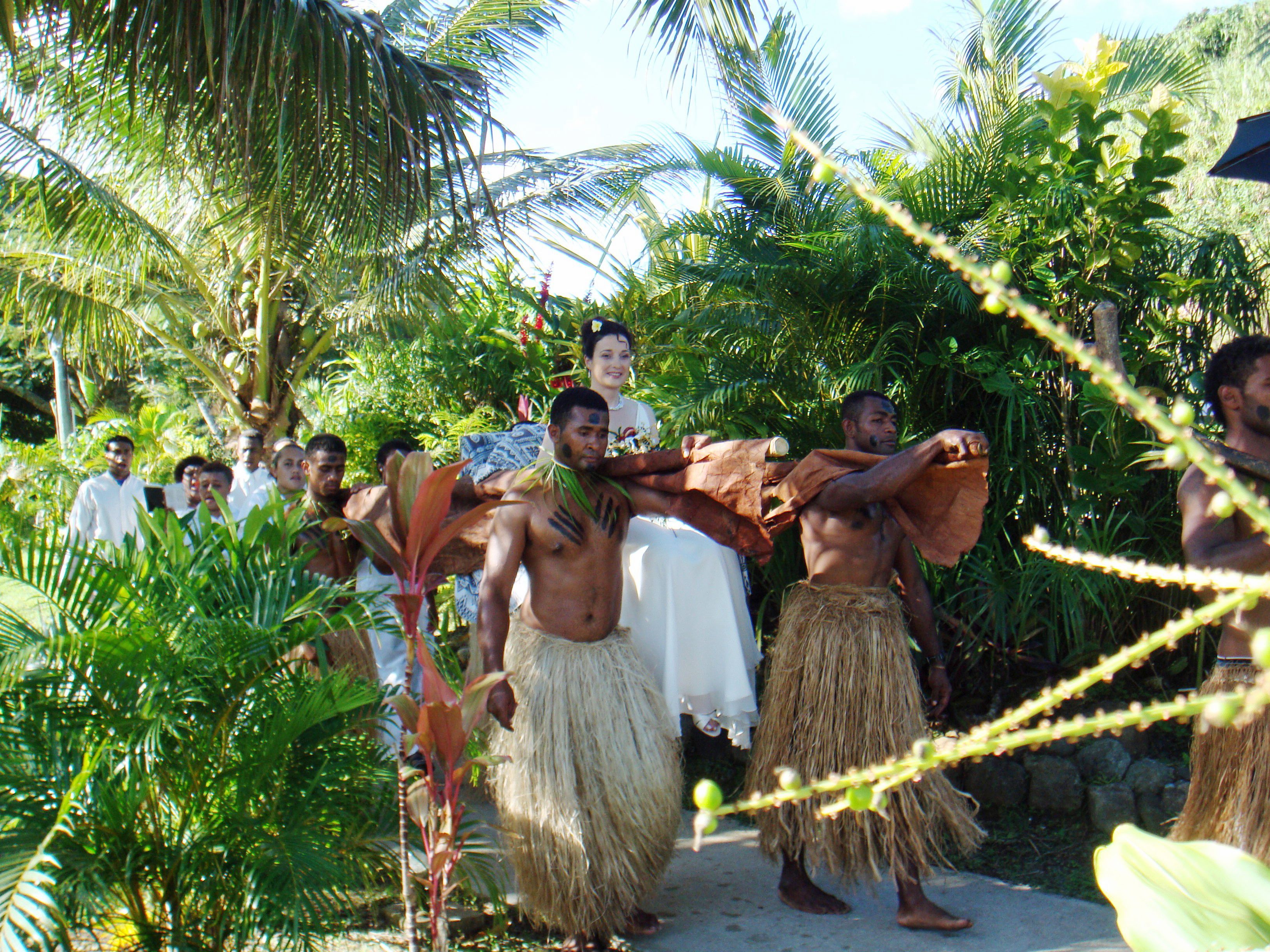 Un grupo de personas vestidas con atuendo tradicional caminando por un entorno verde y exuberante.
