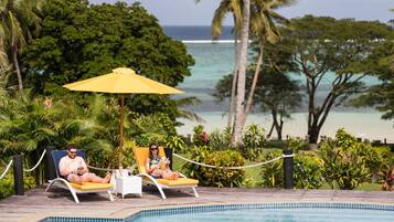 Una piscina al aire libre, sombrillas, sillones reclinables de piscina