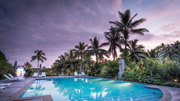 Une piscine avec des chaises longues et des palmiers.
