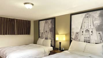 A hotel room with two beds, a nightstand with a lamp, and a large framed picture of a building on the wall.