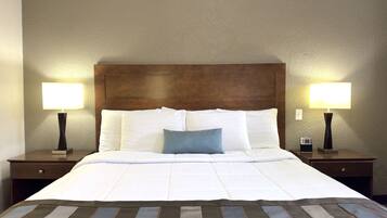A hotel room with a large bed, two bedside tables, and two wall-mounted lamps.