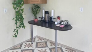 Una cocina con mostrador negro, armarios de madera, una planta colgante y un suelo estampado.