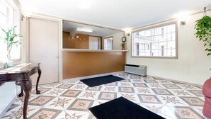 Habitación de hotel con suelo estampado, un mostrador de recepción, un reloj en la pared y un radiador.