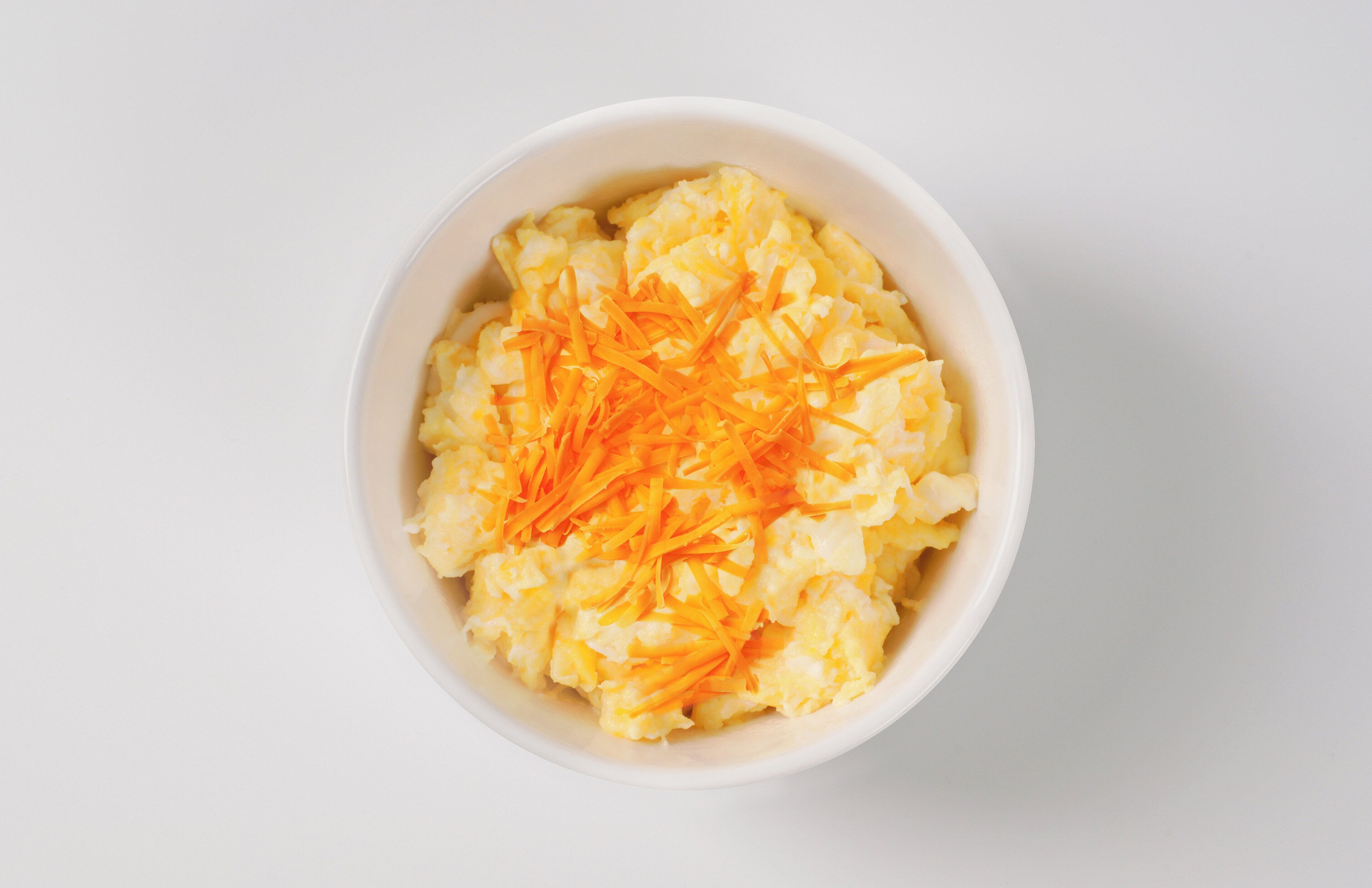 A bowl of mashed potatoes topped with shredded carrots.