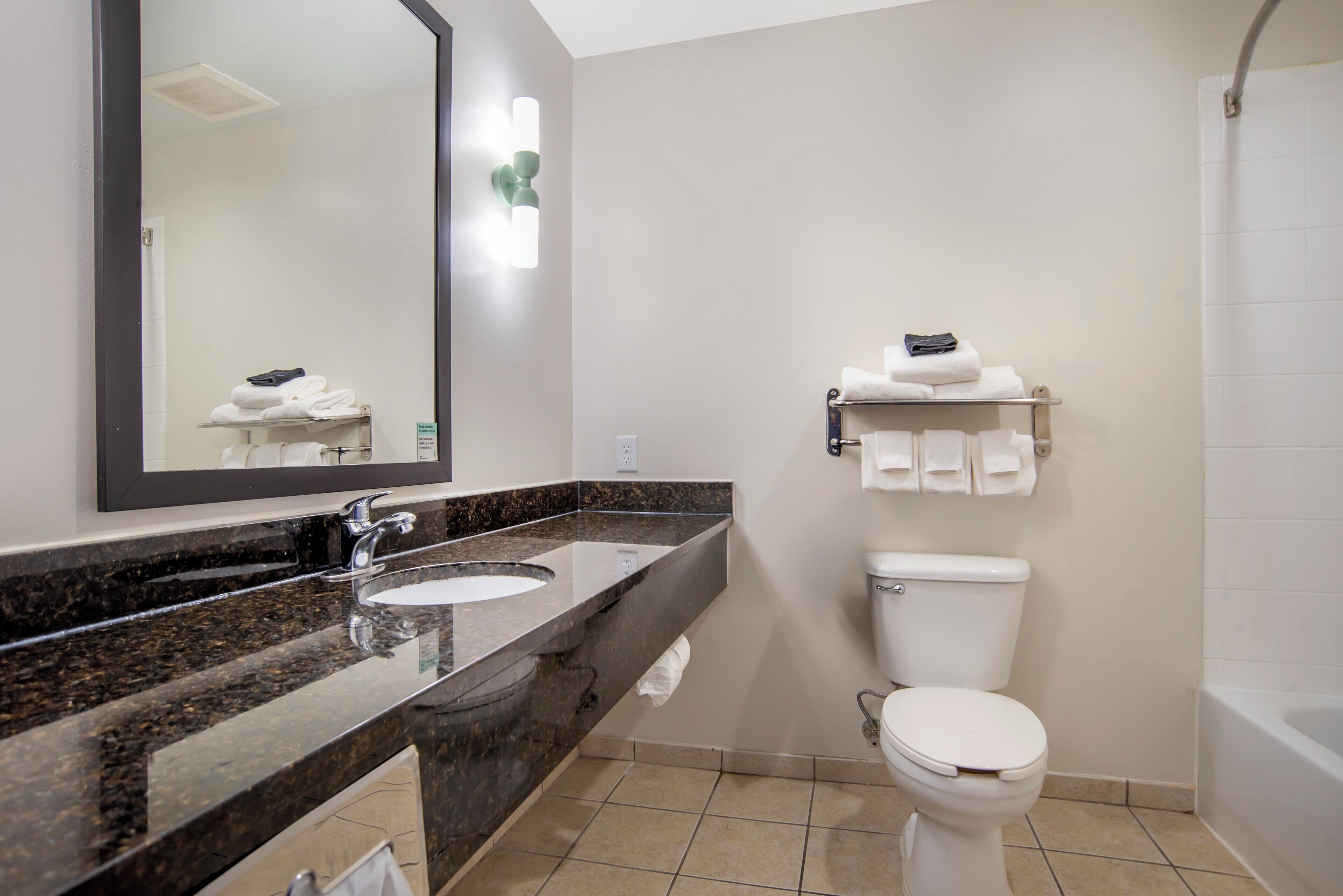 Een badkamer met een dubbele wastafel, toilet en bad.