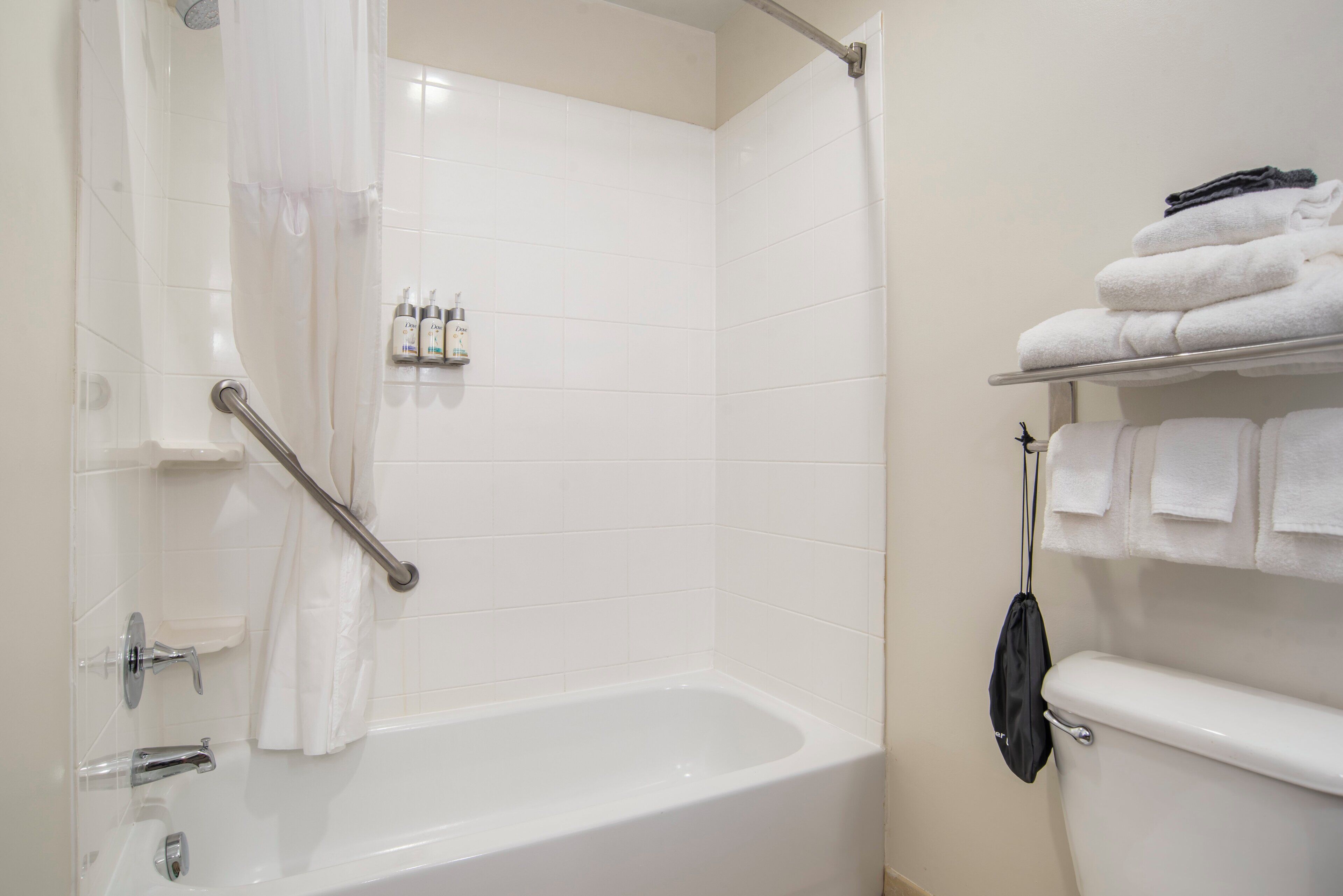 Un baño con bañera, inodoro y un perchero con toallas dobladas.