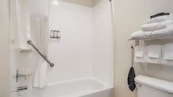 A bathroom with a bathtub, a toilet, and a towel rack with folded towels.