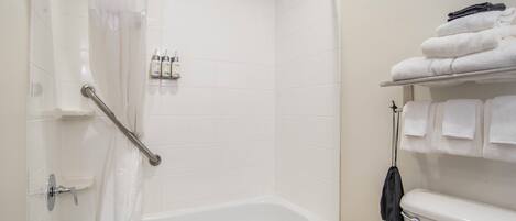 Un baño con bañera, inodoro y un perchero con toallas dobladas.